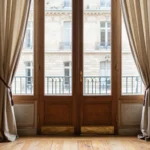 Salon parisien lumineux avec parquet ancien, double porte vitree et moulures